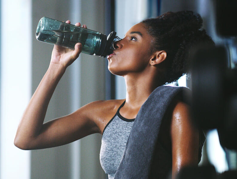 Female athlete drinking a large bottle of water to improve her hydration