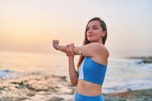 jogger by ocean stretching and wearing a glucose monitor